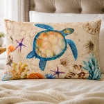 A rectangular decorative throw pillow with a colorful sea turtle and ocean-themed illustration, displayed on a bed with a tufted headboard in the background.